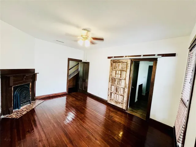 a view of an empty room with wooden floor and fireplace