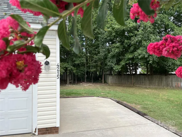 an empty room with wooden floor chandelier and windows