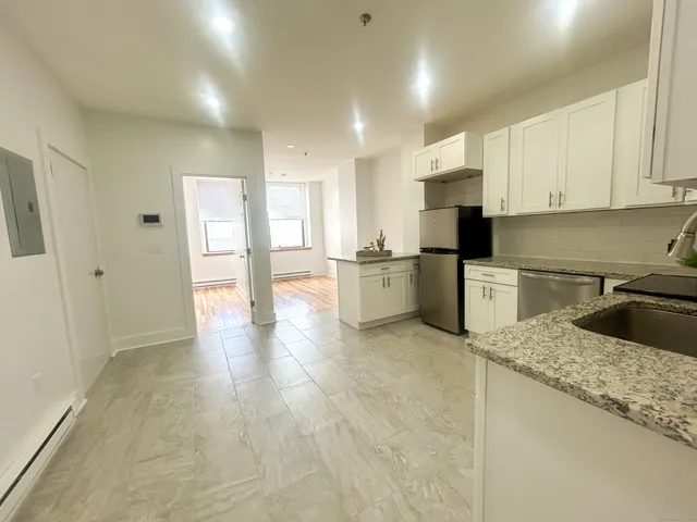 a kitchen with stainless steel appliances granite countertop a refrigerator sink and white cabinets