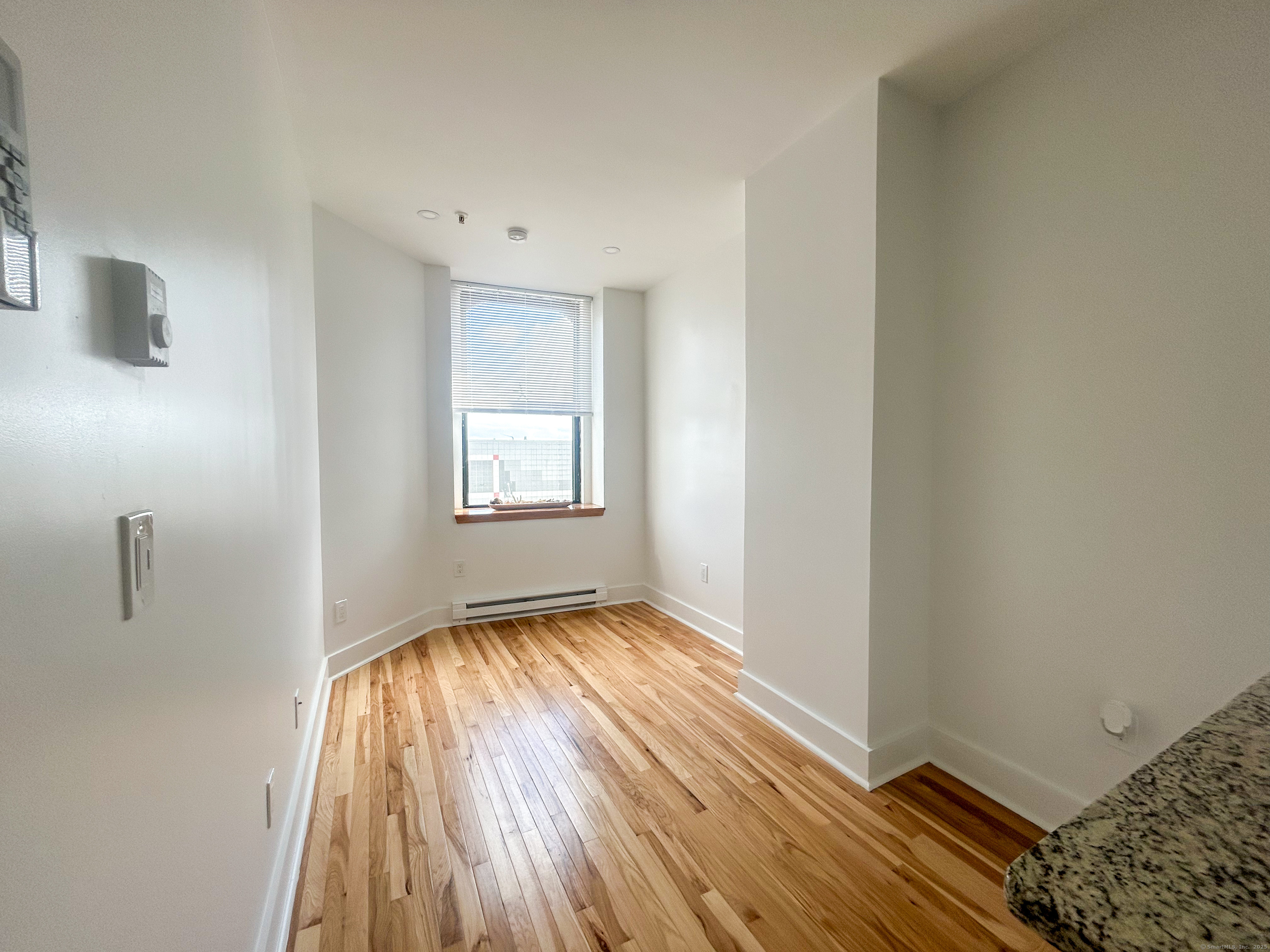 207 Bank Street, Unit 201 New London, CT 06320 - Photo 5 of 12 a view of an empty room with wooden floor and a window