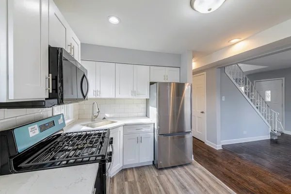 a kitchen with a sink a refrigerator and a stove top oven with wooden floor