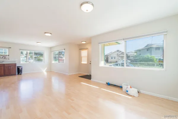 a view of an empty room with a window and wooden floor