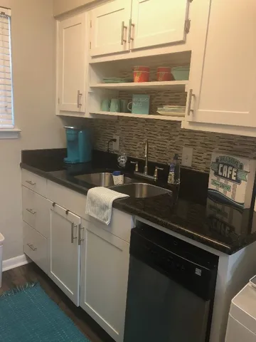 a kitchen with granite countertop white cabinets and white appliances