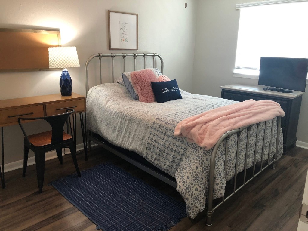 2401 Manor Road, Unit 117 Austin, TX 78722 - Photo 5 of 7 a bedroom with a bed a table and painting on the wall