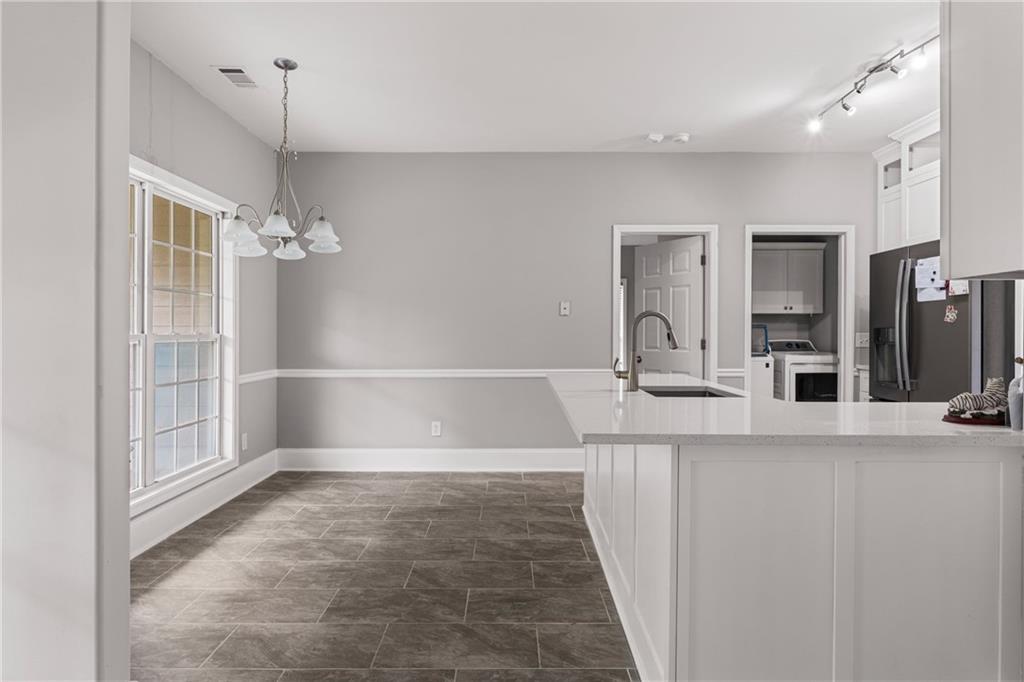 1449 Cummings Road Smiths Station, AL 36877 - Photo 13 of 28 Open-concept kitchen and dining area featuring a kitchen island with sink, white shaker cabinets, and tile flooring