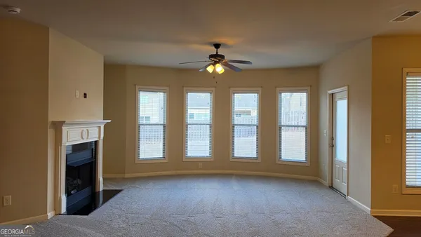 a view of an empty room with kitchen and window