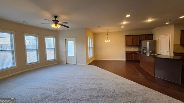 a kitchen with stainless steel appliances granite countertop a refrigerator a sink dishwasher a stove and white cabinets with wooden floor