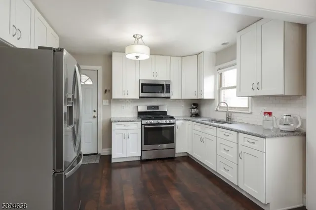 a kitchen with granite countertop a stove a sink and a refrigerator