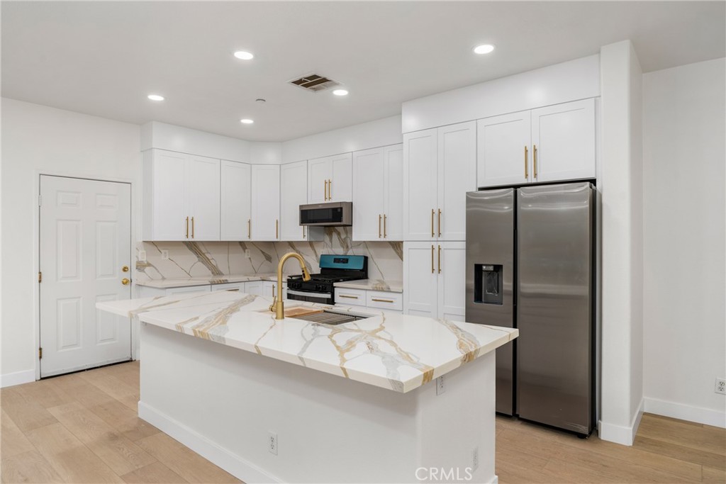 312 Quail Ridge Irvine, CA 92603 - Photo 11 of 20 a kitchen with kitchen island a refrigerator sink stove and microwave