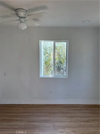 an empty room with wooden floor fan and windows