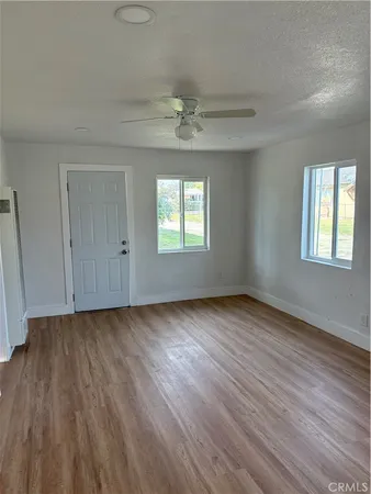 an empty room with wooden floor chandelier fan and windows