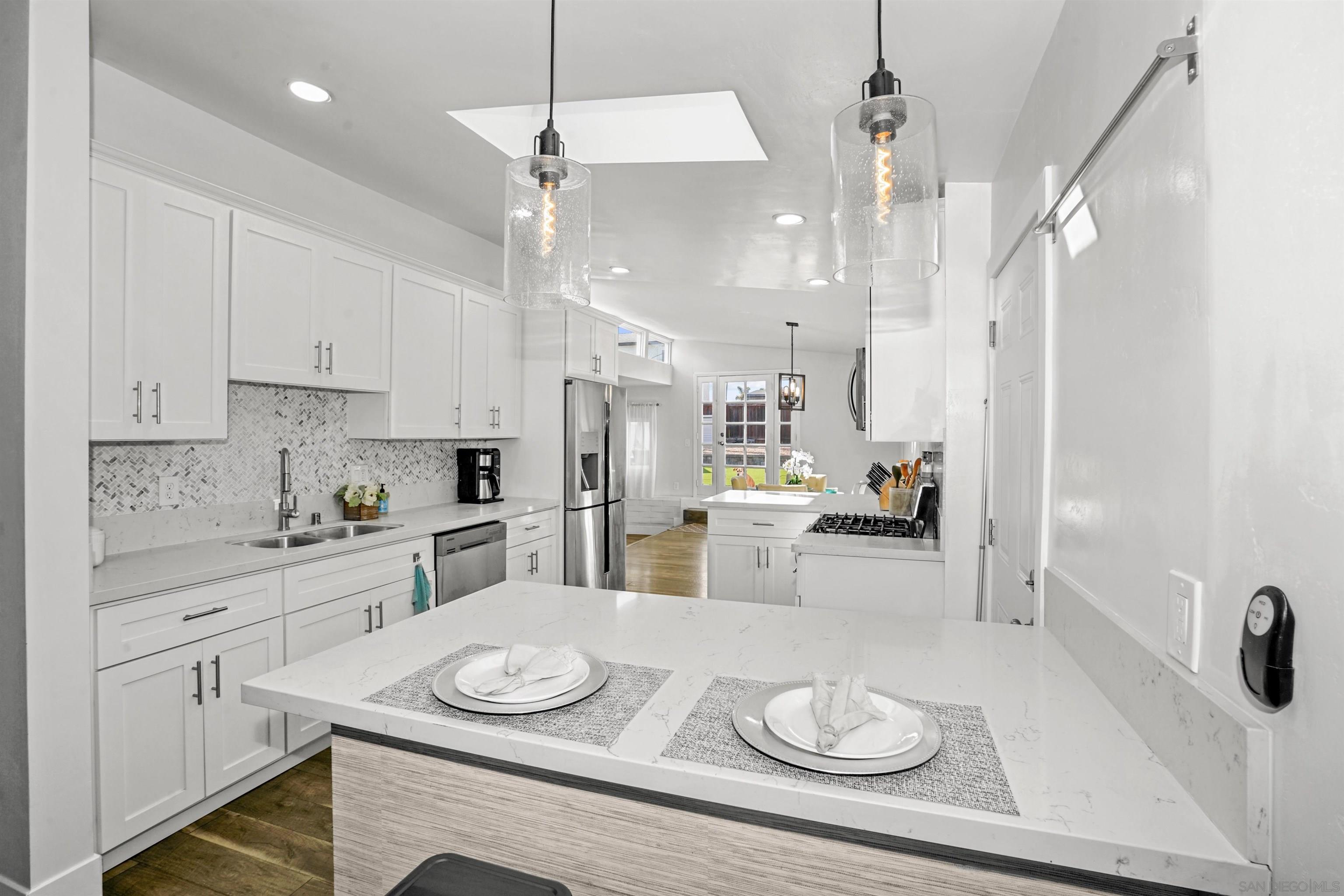 a kitchen with stainless steel appliances kitchen island granite countertop a table chairs and white cabinets