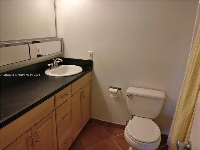 a bathroom with a granite countertop toilet sink and mirror