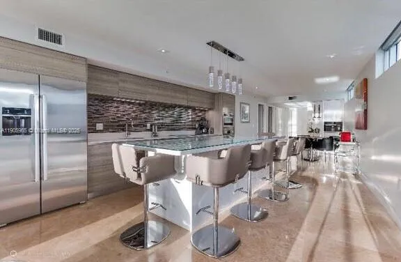 a kitchen with stainless steel appliances kitchen island granite countertop a table chairs in it and a sink