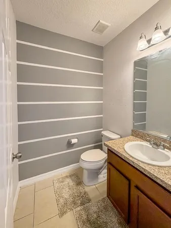 a bathroom with a granite countertop sink toilet and a mirror