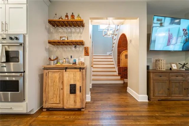 a kitchen with stainless steel appliances kitchen island granite countertop a refrigerator a stove a sink a dining table and chairs with wooden floor