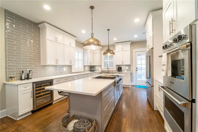 a large kitchen with kitchen island a large counter space a stove a sink and a chandelier
