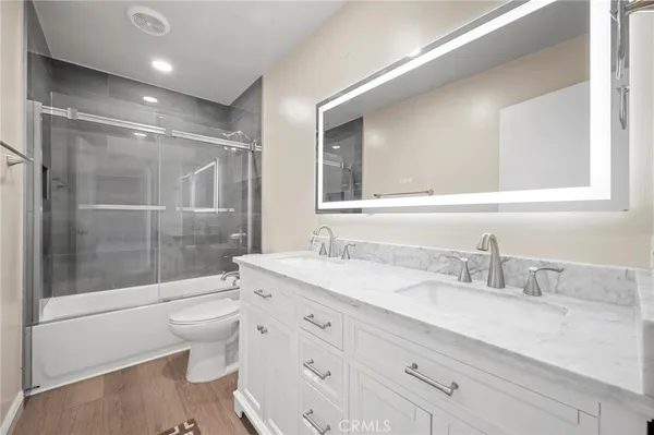 a bathroom with a granite countertop sink a toilet and shower