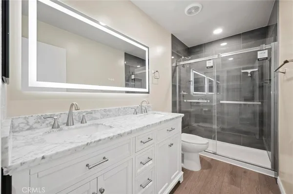 a bathroom with a granite countertop sink a toilet a mirror and shower