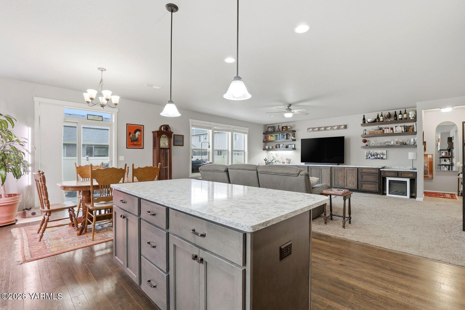 104 Bravo Street Moxee, WA 98936 - Photo 10 of 27 a view of a dining room and livingroom with furniture wooden floor a rug a fireplace and a chandelier