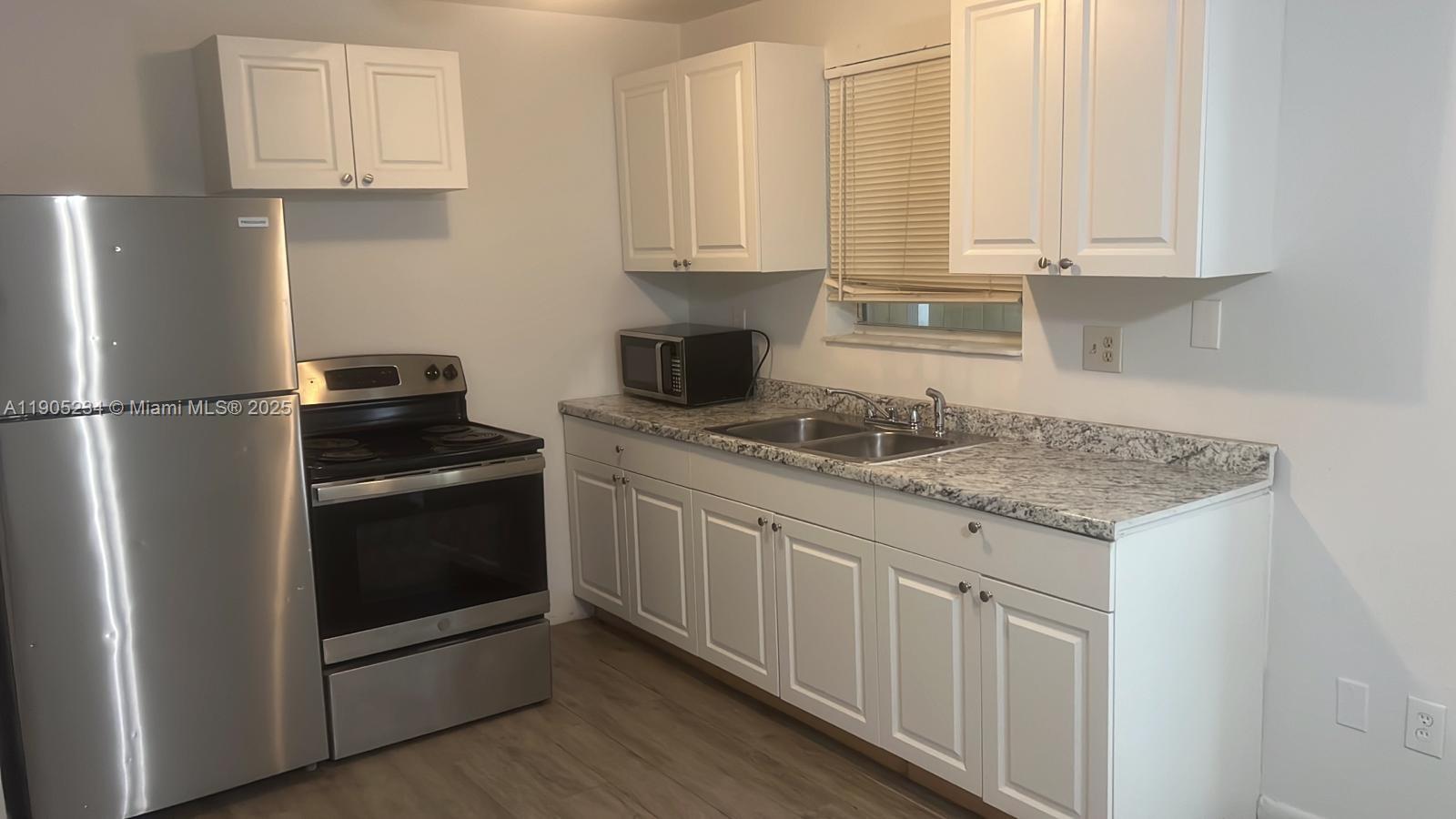 7230 Northwest 3rd Street, Unit 4 Miami, FL 33126 - Photo 4 of 13 a kitchen with granite countertop a sink stove and refrigerator
