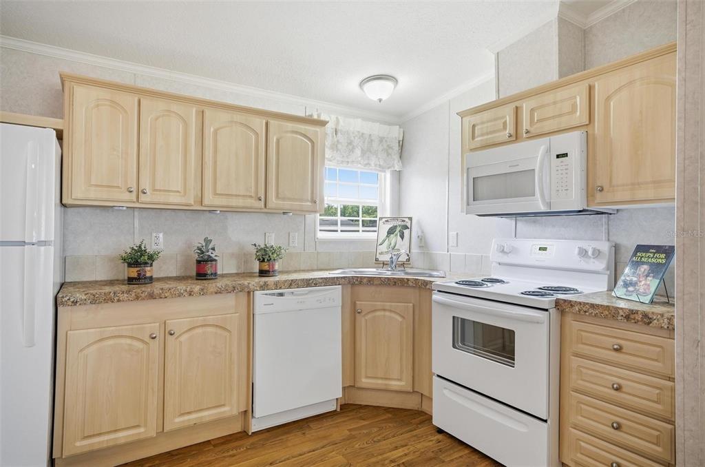55716 Keith Street Astor, FL 32102 - Photo 12 of 32 a kitchen with granite countertop white cabinets sink and stainless steel appliances