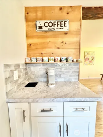 a living room with kitchen island granite countertop wooden floor and a large window