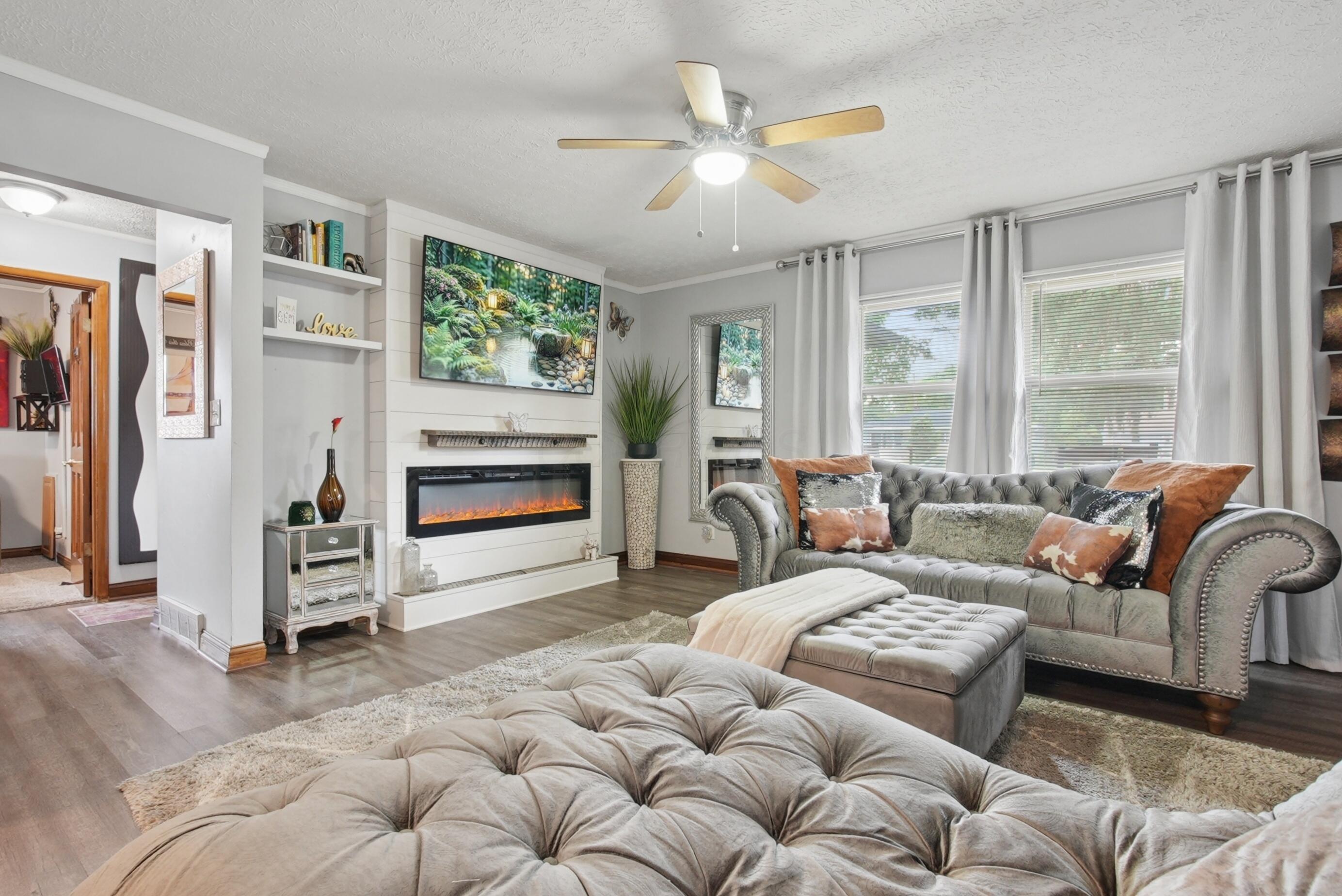 A custom built-in electric fireplace with a shiplap surround and large picture window.