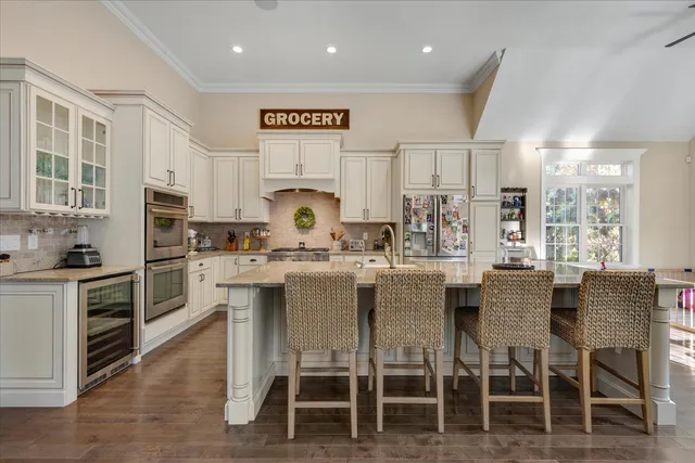 a kitchen with stainless steel appliances kitchen island granite countertop a table chairs sink and cabinets