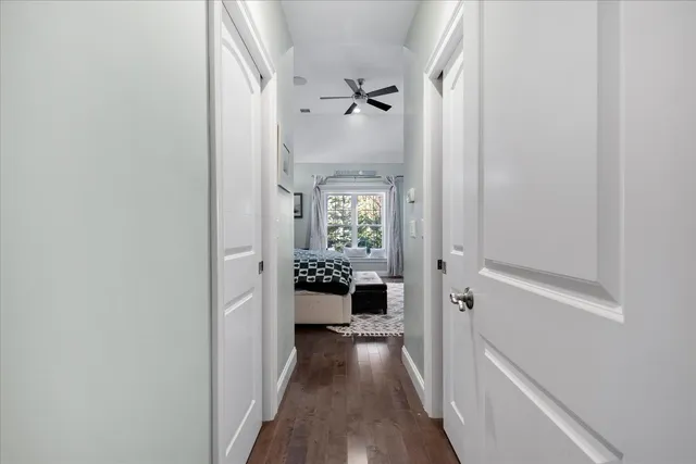 a view of a hallway with wooden floor and a bathroom