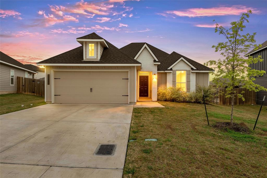 Single-story residence featuring a two-car garage with decorative hardware, a covered entry, and a dormer window