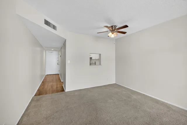 an empty room with a chandelier fan and windows