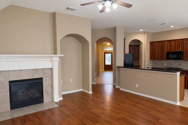 a view of an empty room with kitchen and fireplace