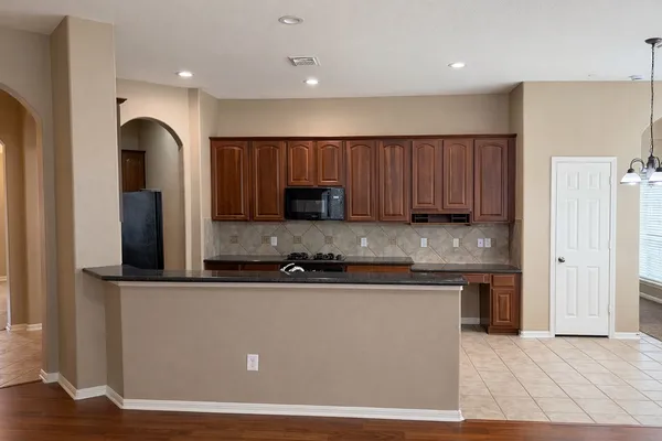 a kitchen with stainless steel appliances granite countertop a refrigerator a sink a stove a microwave and wooden cabinets
