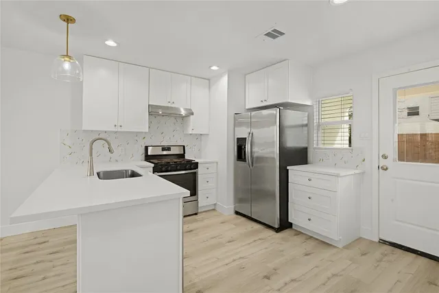 a kitchen with white cabinets and stainless steel appliances