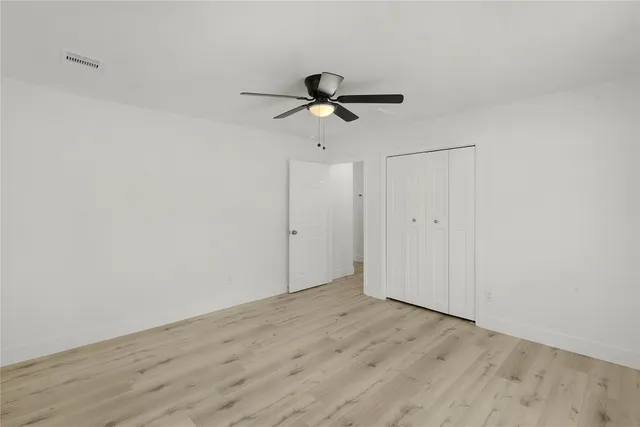 a view of a room with wooden floor and a ceiling fan