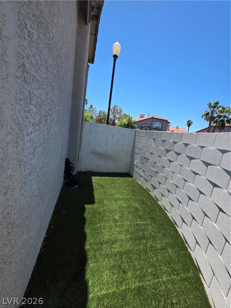 2275 Ramsgate Drive Henderson, NV 89074 - Photo 7 of 84 A private yard with vibrant green artificial turf and unique block retaining walls offers a serene outdoor retreat.