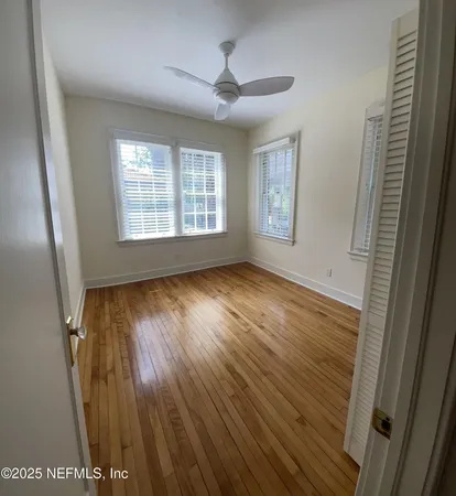 a view of an empty room with wooden floor and a window