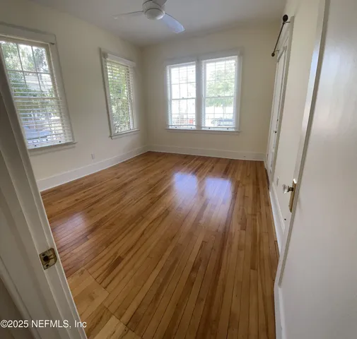 a view of an empty room with wooden floor and a window