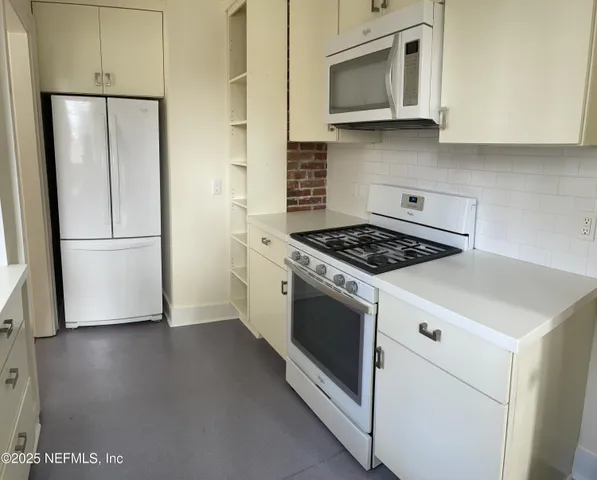 a kitchen with granite countertop a refrigerator and a stove top oven