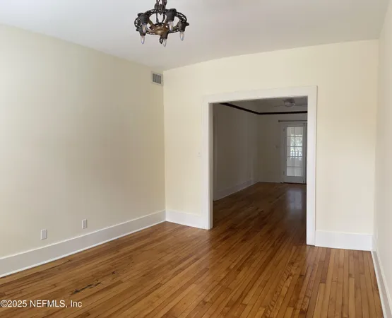 a view of a room with wooden floor and a chandelier