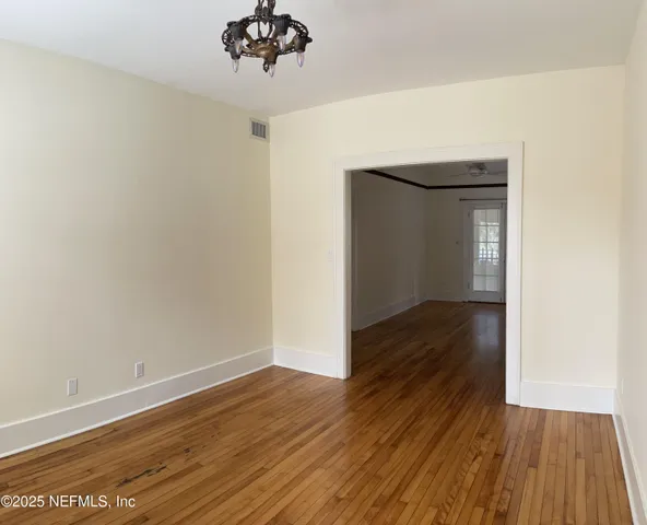 a view of a room with wooden floor and a chandelier