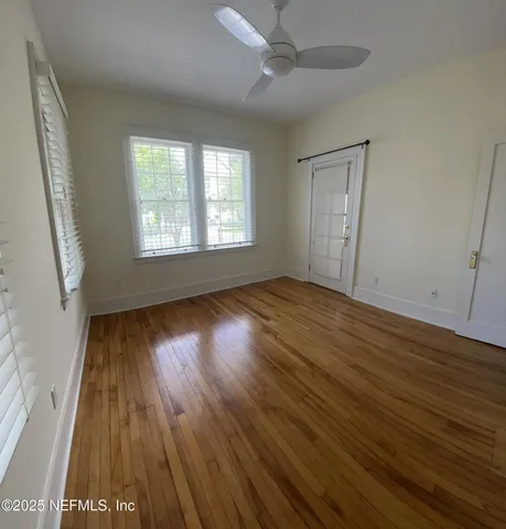 a view of an empty room with wooden floor and a window