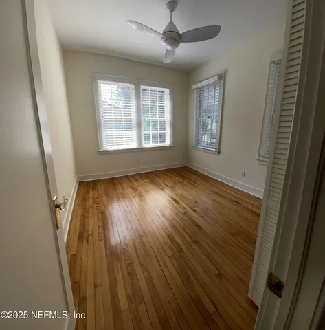 a view of hallway with window and wooden floor