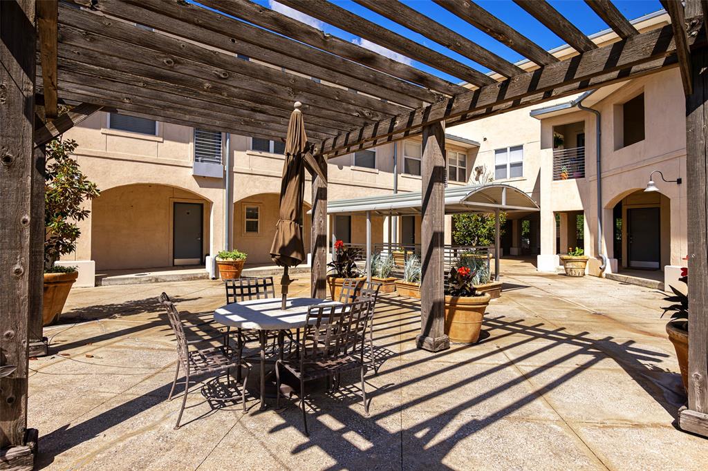3922 Gilbert Avenue, Unit 214 Dallas, TX 75219 - Photo 23 of 27 Expansive outdoor courtyard featuring a large wooden pergola, concrete paver flooring, and arched architectural details