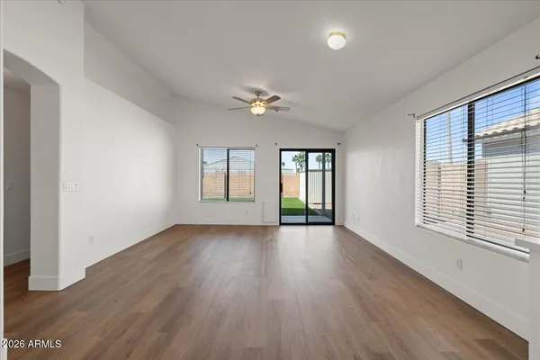 a view of an empty room with a window and wooden floor