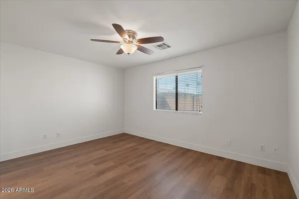 a view of empty room with wooden floor and fan