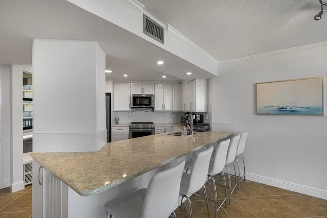 a kitchen with stainless steel appliances granite countertop a kitchen island a stove a sink a dining table and chairs