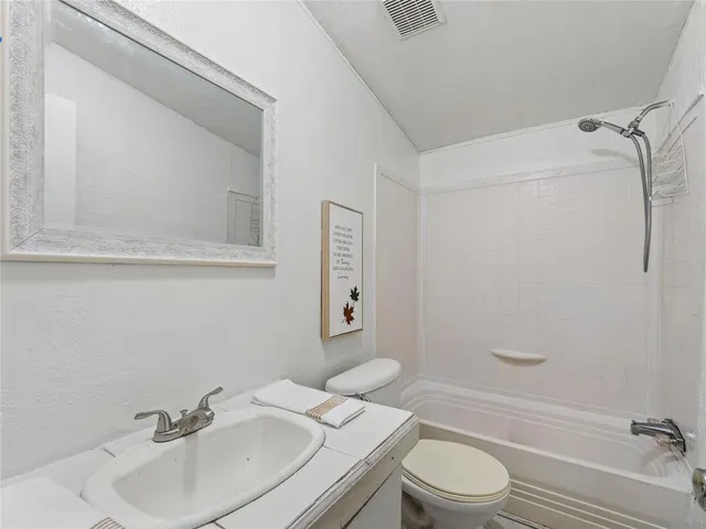 a bathroom with a granite countertop toilet sink and mirror