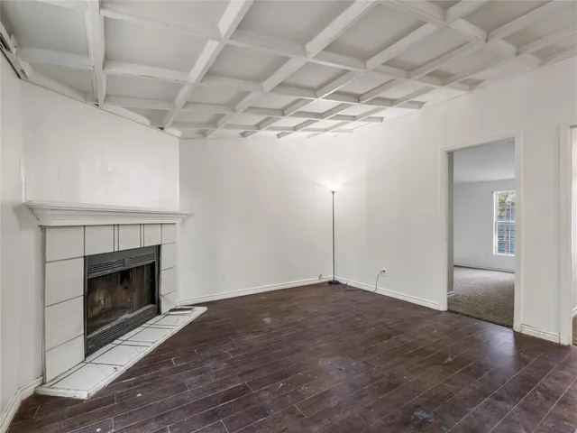 a view of empty room with wooden floor and fireplace